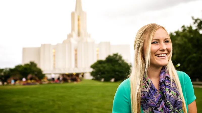 A woman stands in front of a temple of the Church of Jesus Christ of Latter-day Saints