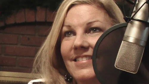 A smiling woman beside a radio microphone.