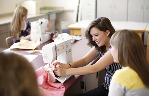 High school sewing class full of young women.