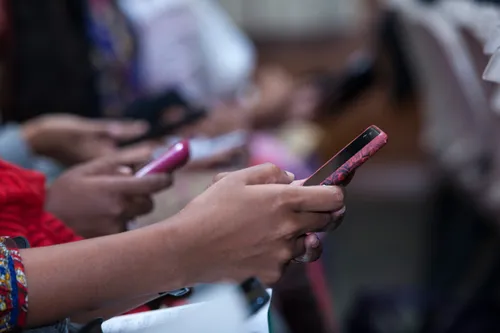 Hands of sister missionaries holding cell phones.