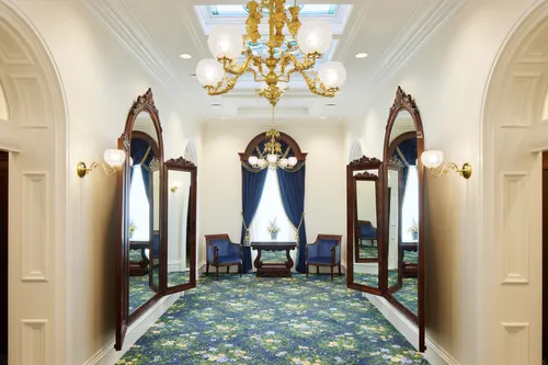 Interior image of the St. George Utah Temple. The image features the Brides’ Room. There are large windows on both sides. A chandelier hinges in the center of the ceiling. 