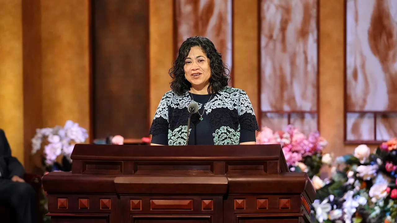 Sister Aburto stands at pulpit to give conference address