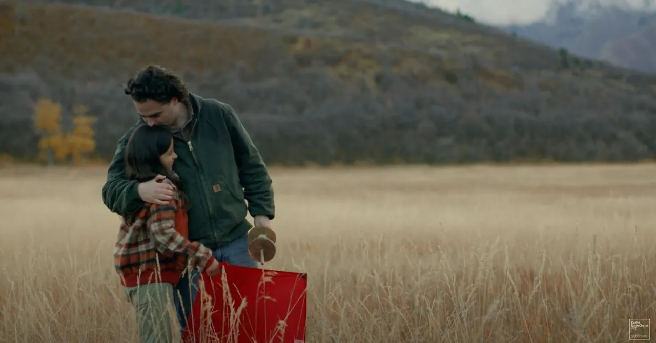 A father with his daughter in a field hold a kite in the Parable of the Kite video