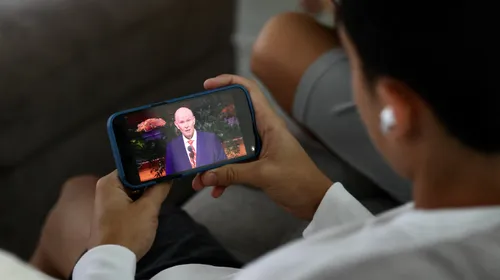 young man watching general conference on their phone