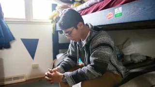 A young man sits on his bed and prays to his Father in Heaven.