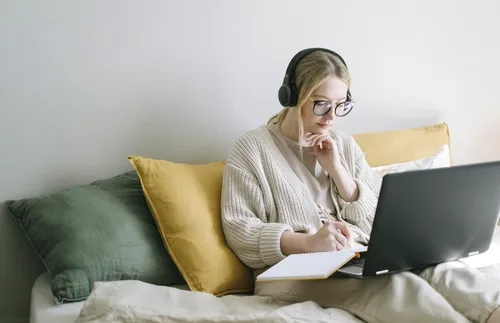 Woman watching laptop and taking notes