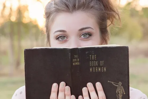 young adult woman holding an old Book of Mormon