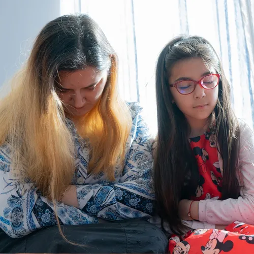 a woman praying with her daughter