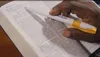 hand with pen over open scriptures
