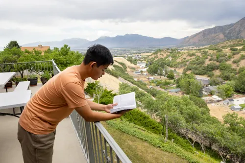 young man studies the scriptures outside