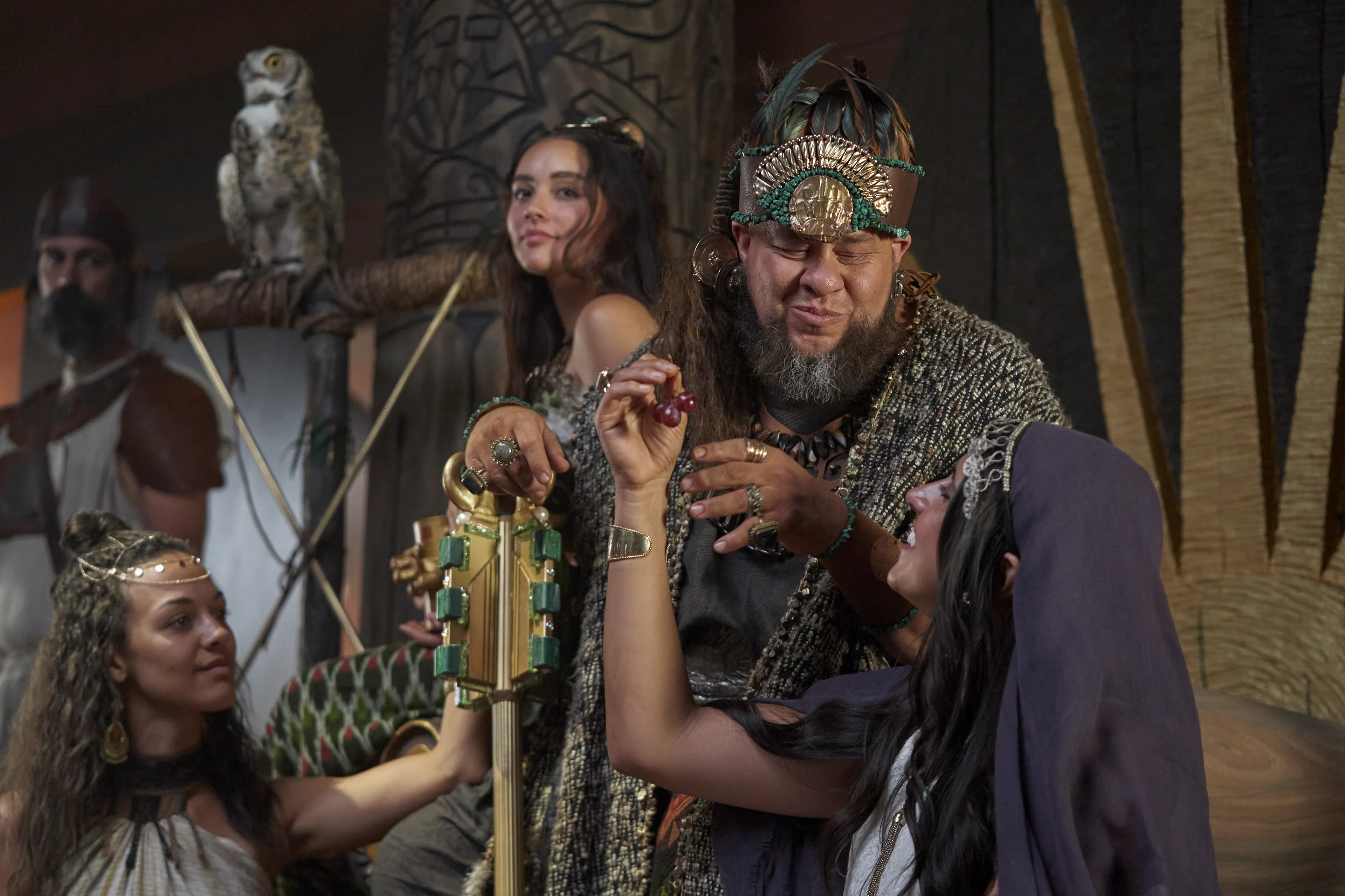 King Noah feasts with a large crowd of priests and women in his throne room.