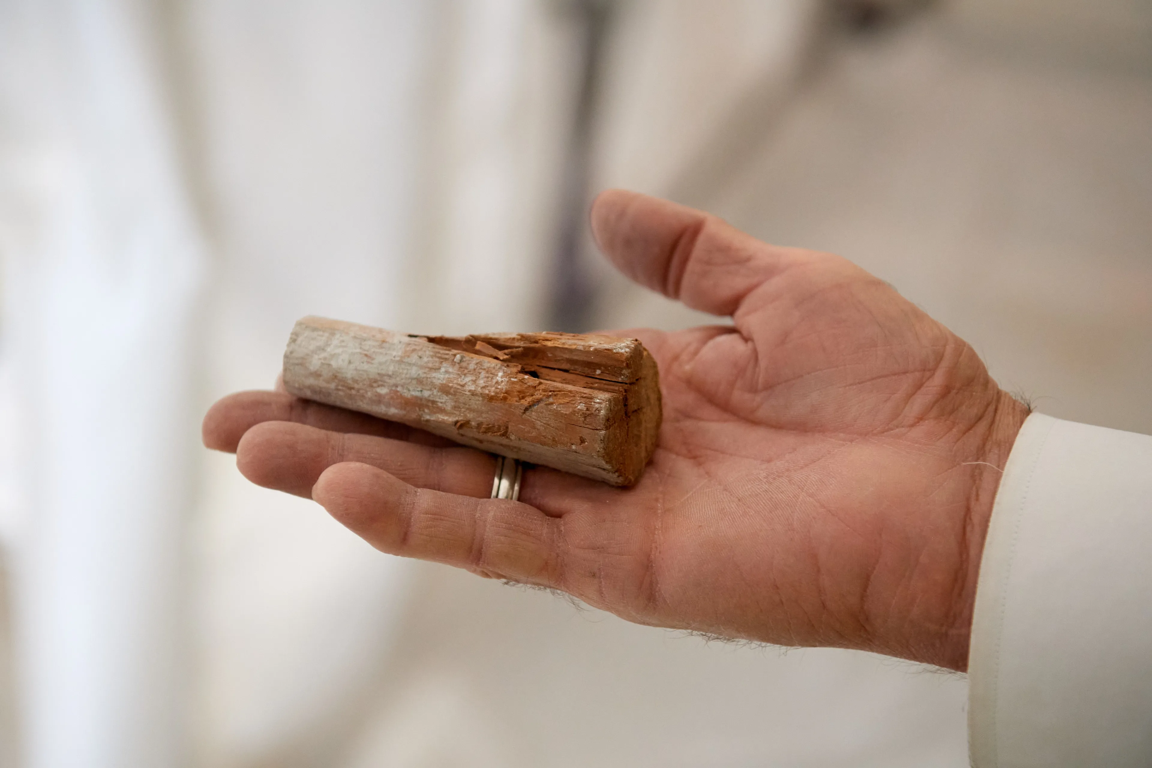 Construction on the Salt Lake Temple during September, 2020. A construction worker holds old wood pieces in their hands. 
