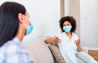 two female friends wearing face masks and talking