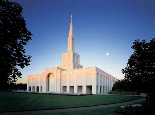 The Toronto Ontario Temple in the late evening, with trees on either side and the moon above.