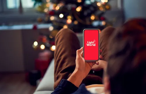 a man studying a phone screen with the Light the World logo