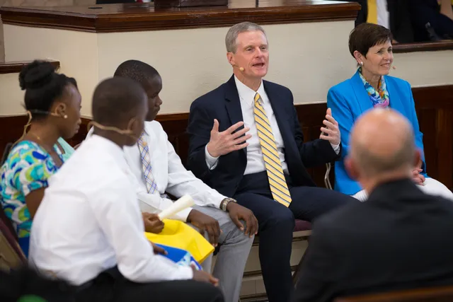 Elder David A. Bednar of the Quorum of the Twelve Apostles and his wife, Sister Susan Bednar, enjoy chatting with teenagers during a youth devotional on August 31, 2019, in Port-au-Prince, Haiti.