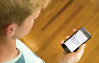 young person reading the scriptures on a smartphone