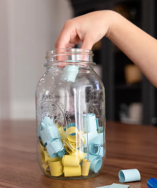 Child’s hand taking paper slip out of a glass jar
