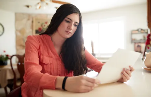 a woman sitting at a table and reading her patriarchal blessing