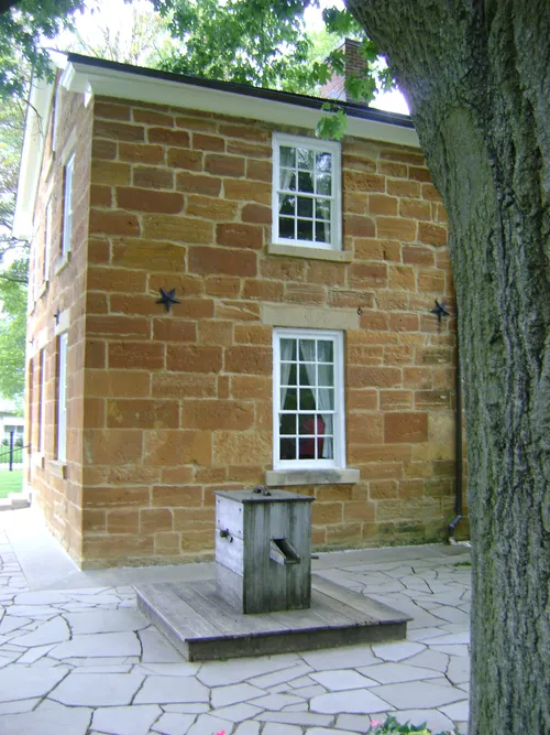 A side view of Carthage Jail, a two-story brick building with white windows and black metal stars.
