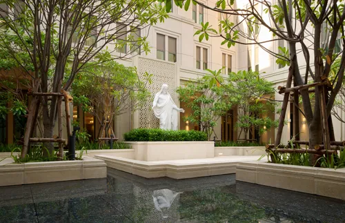a Christus statue next to a reflecting pool