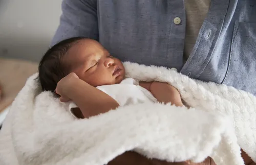 person holding a newborn baby wrapped in a blanket