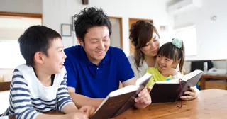 usa ka amahan ug inahan nga nagbasa sa mga kasulatan uban sa ilang mga anak