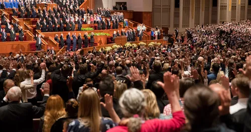 Members stand as they raise their hand to sustain new president of the Church in solemn assembly.