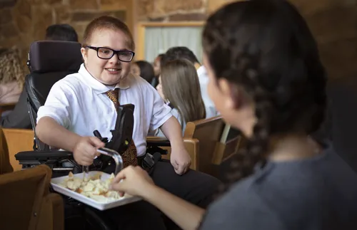 a young man in a wheelchair helps to pass the sacrament