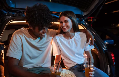 a young couple sitting in a car and laughing together
