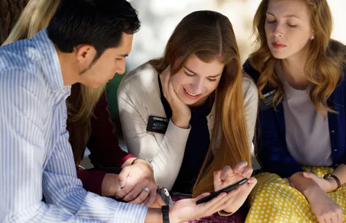 sister missionaries and a couple looking at a phone