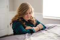 A woman kneels in her room praying for comfort from God