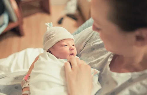 mother in hospital bed holding newborn