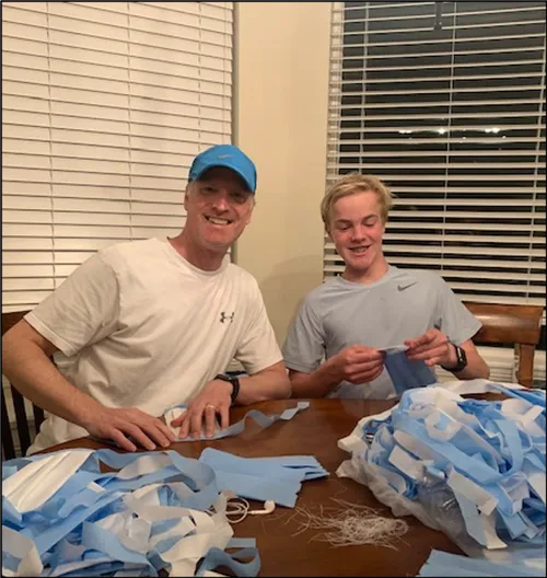 father and son sewing masks