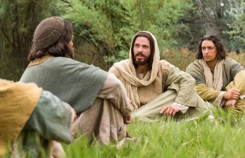Christ sits in a field with His disciples