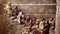 Men and women listen to Paul's teachings of Jesus Christ.  They are seated on stairs.