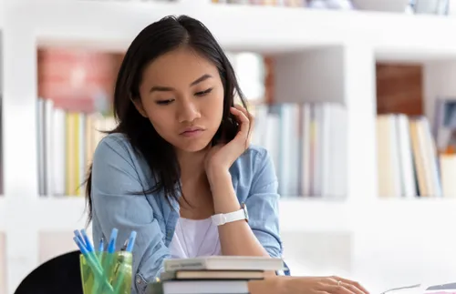 young woman looking at a stack of books