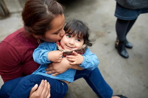 mother kissing daughter on cheek