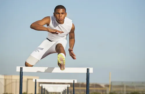 young man running hurdles