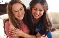 Two women hug one another as they greet each other at church