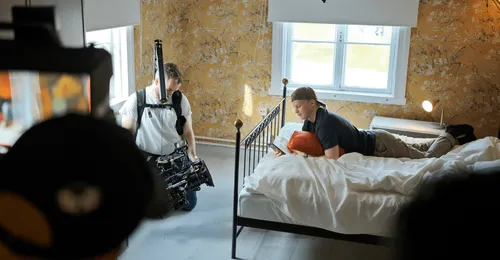 man filming young man using a phone on his bed