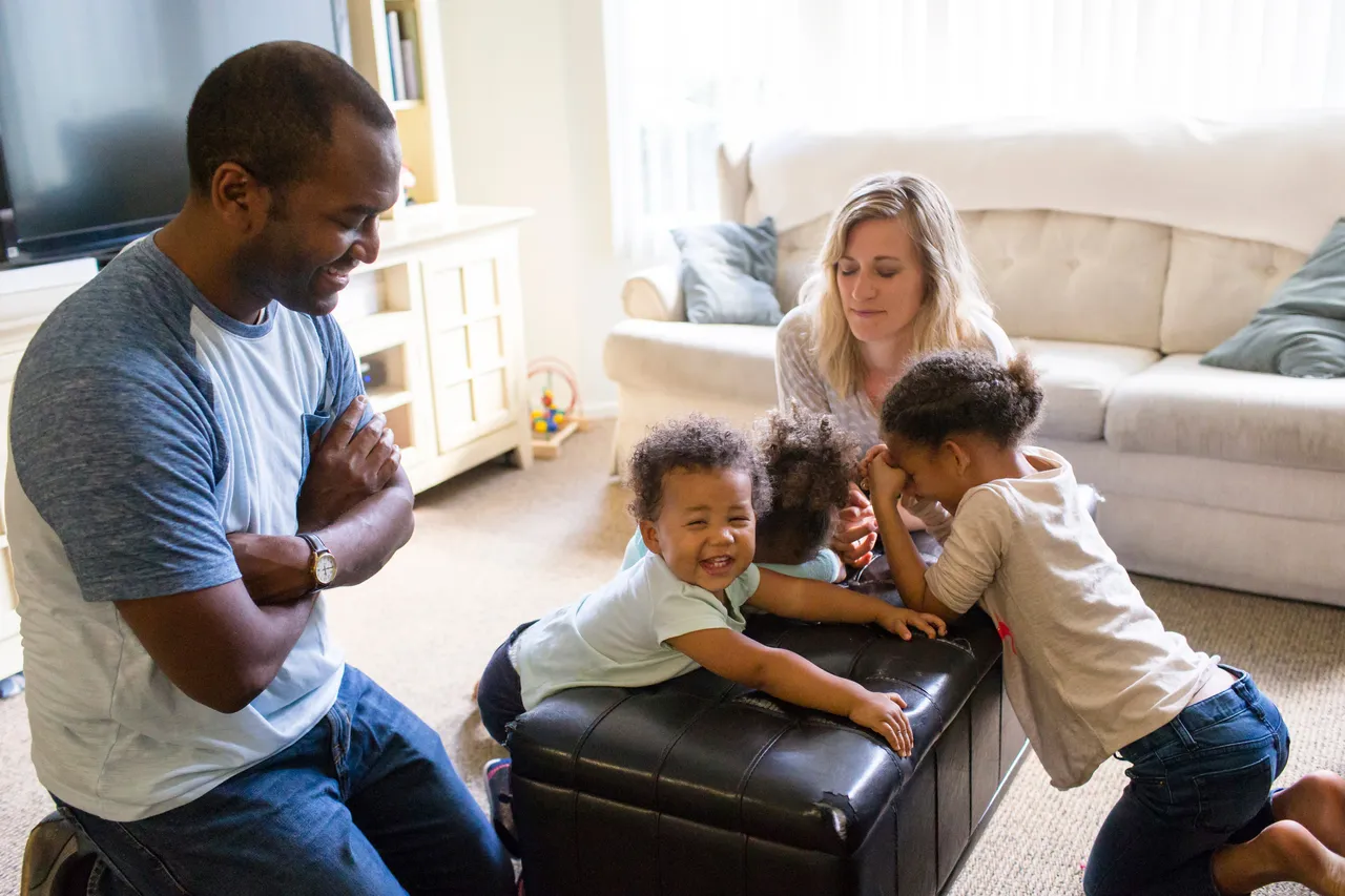 A young family pray together in their living room