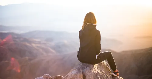 girl sitting on top of a mountain
