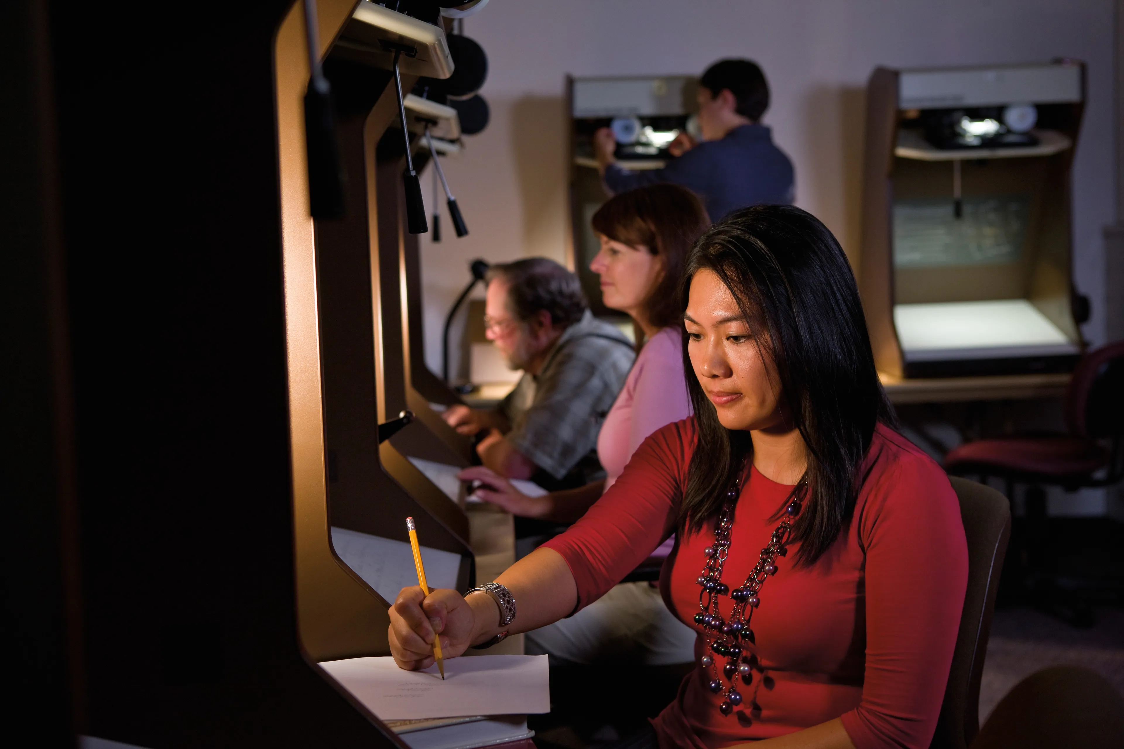 A young woman looks on a microfilm reader while doing family history research.