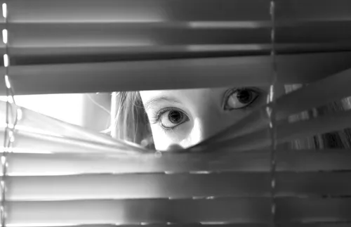 woman looking through blinds