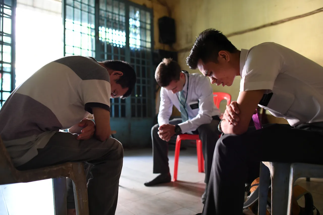 Two elder missionaries pray with a man to help him trust in the Lord