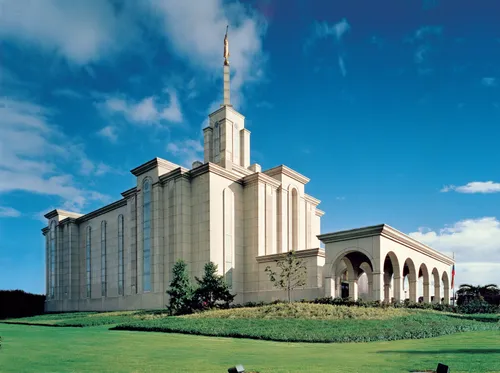 A green lawn surrounding the Bogotá Colombia Temple, with a partly cloudy sky overhead.