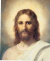 Frontal head and shoulders portrait of Jesus Christ. Christ is depicted wearing a pale red robe with a white and blue shawl over one shoulder. Light emanates from His face.
