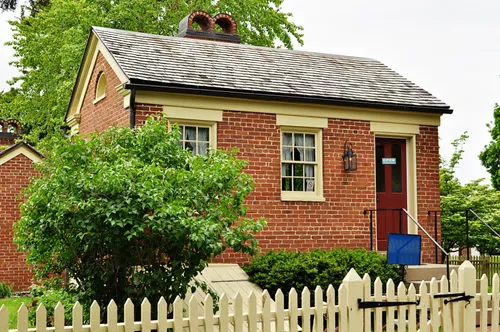 A small red-brick building in Nauvoo, Illinois, known as the Scovil Bakery, sits behind a white picket fence.