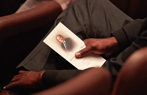 hand holding funeral program